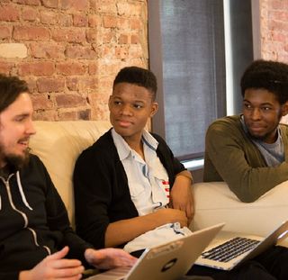 A Tumblr engineer and two Black folks sitting by a table
    talking about code.